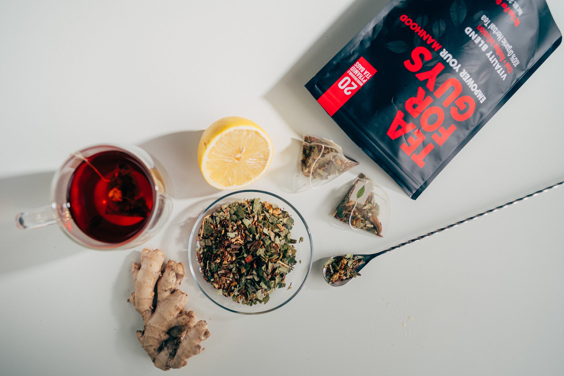 Tea For Guys Vitality Blend flat lay with brewed tea, lemon, ginger, and loose-leaf herbal ingredients